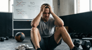 Persona entrenando en un gimnasio con expresión de frustración por no ver resultados pese a entrenar y comer bien